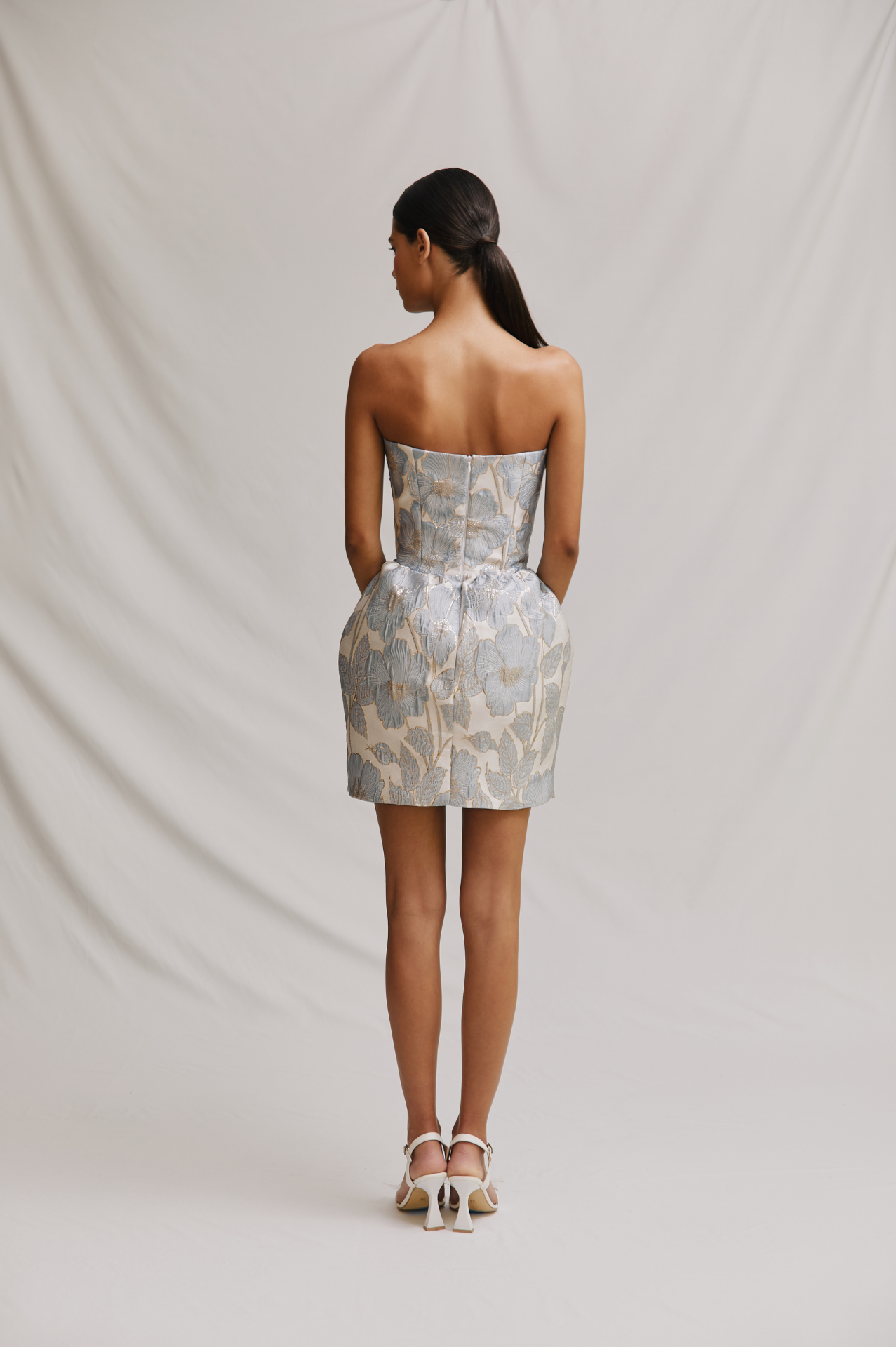 Woman wearing a strapless floral dress against a plain background